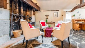 A cozy room with a stone floor, a fireplace, and a dining area with chairs and a table.