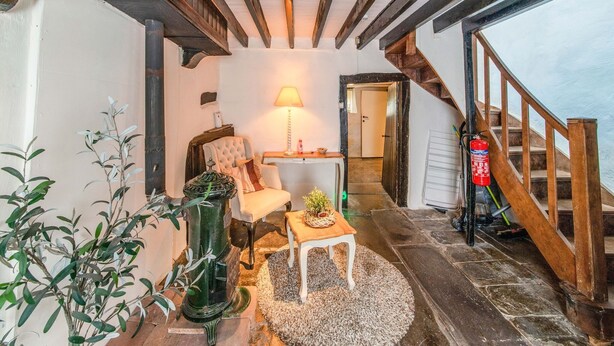 A cozy interior with a fireplace, a comfortable chair, a small table, and a staircase leading to an upper level.