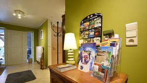 A reception desk with a lamp, a bulletin board with travel brochures, and a door leading to another room. - Beautiful gîte in former farmhouse with garden (Sainte ode)
