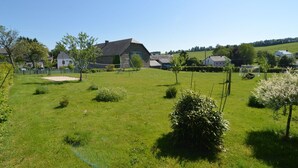 A grassy field with a stone building, a swing set, and a small tree. - Beautiful gîte in former farmhouse with garden (Sainte ode)