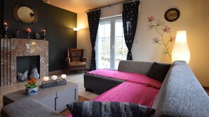 Un salon chaleureux avec une cheminée, un canapé, un fauteuil et une table à manger.
