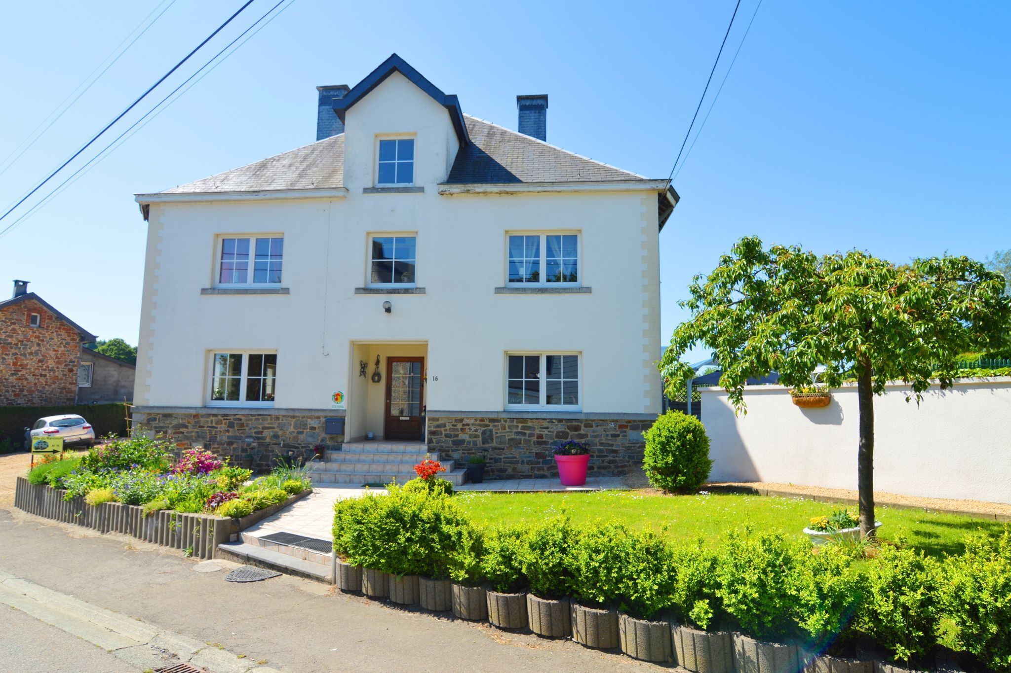 A two-story house with a white exterior, a stone foundation, and a small front porch.