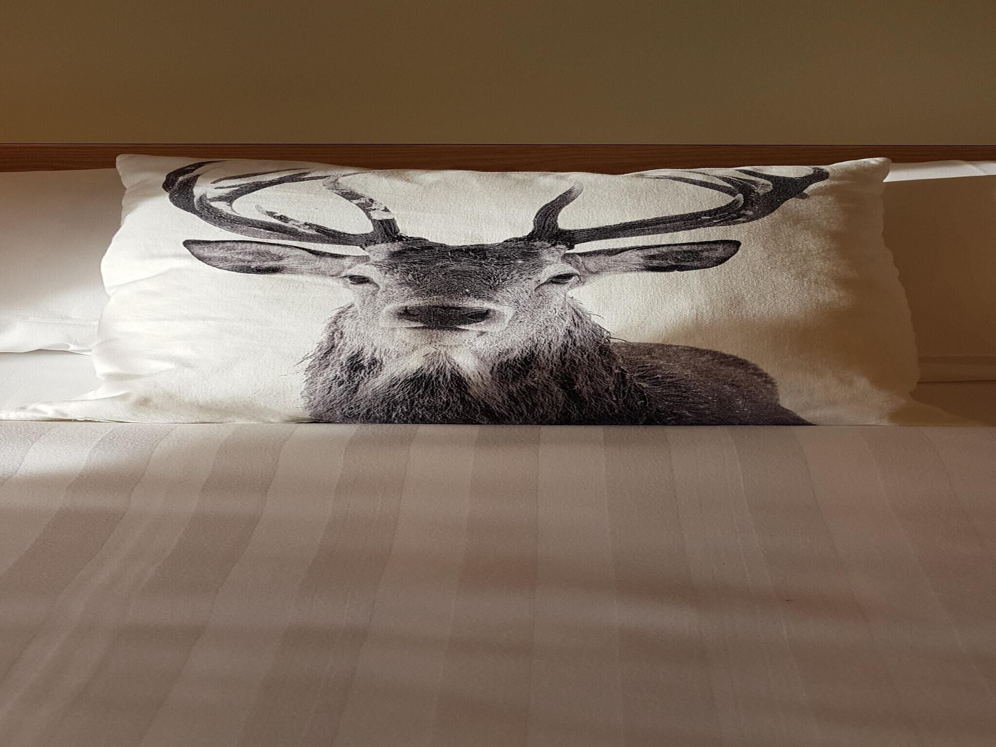 A pillow with a deer design on a bed.