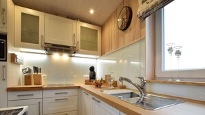 A modern kitchen with white cabinets, a stainless steel sink, and a wooden countertop. - Tranquil Stay in Vielsalm (Vielsalm)