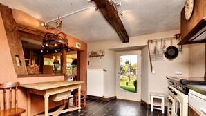 A kitchen with a wooden table, a stove, and a view of the outside.