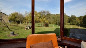A room with a large window overlooking a grassy yard with trees and a stone building.