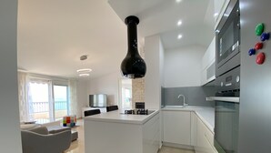 A modern kitchen with a central island, built-in appliances, and a dining area with a sofa and table.