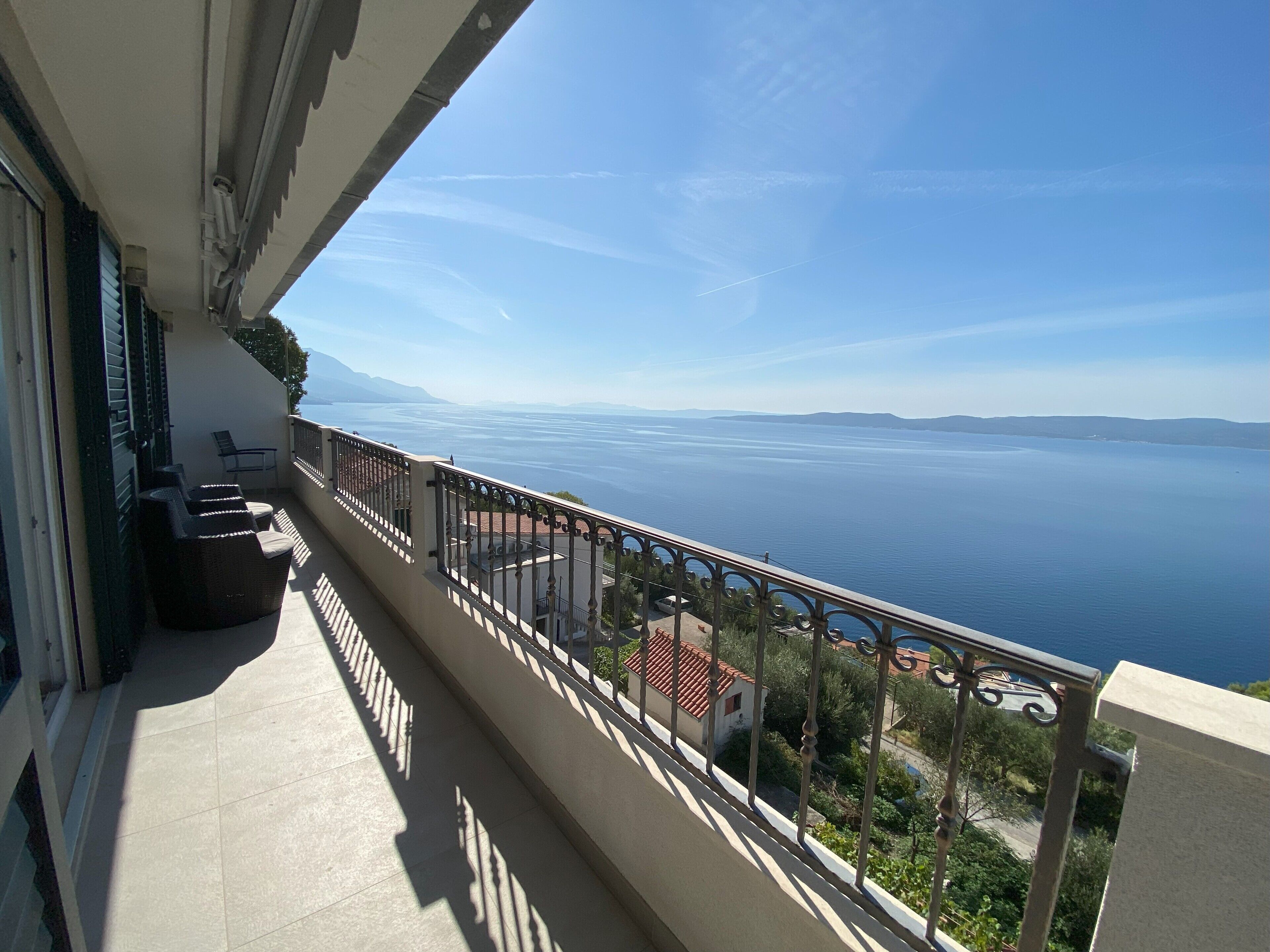 A balcony with a view of a large body of water and distant mountains.