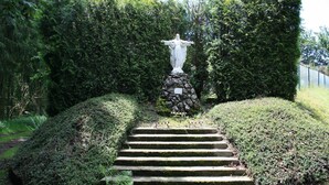 A stone staircase leading to a statue surrounded by lush greenery. - Cozy Forest Cottage in Awenne (Awenne)