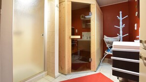 Une pièce avec un sauna, un meuble en bois, un tapis rouge et une chaise blanche.