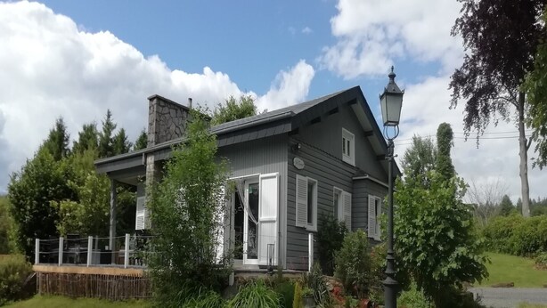 A two-story house with a porch, surrounded by a well-maintained garden and trees.