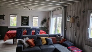 A cozy room with a sofa, a dining table with chairs, and a window with a view of trees.
