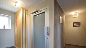 Ein modernes Hotelzimmer mit einer Schiebetür aus Glas, Holzvertäfelung und einem gerahmten Bild an der Wand.