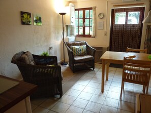 Een gezellige woonkamer met rieten meubels, een eettafel en een raam met gordijnen.