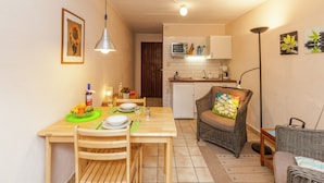 A compact kitchen with a microwave, sink, and cabinets. A dining area with a table, chairs, and a hanging light fixture is visible. - Cozy Escape in Bohon (Bohon-Durbuy)