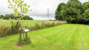 A grassy field with a wooden signpost and a power line tower in the background. - Cozy Escape in Bohon (Bohon-Durbuy)