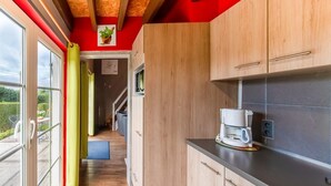 Een moderne keuken met houten kastjes, een koffiezetapparaat en uitzicht op buiten.