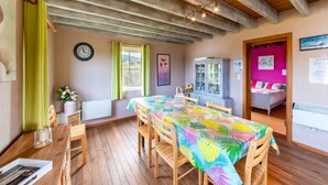 Een gezellige kamer met een houten plafond, een eettafel met stoelen, een kast met glazen deuren en een bed met roze beddengoed.