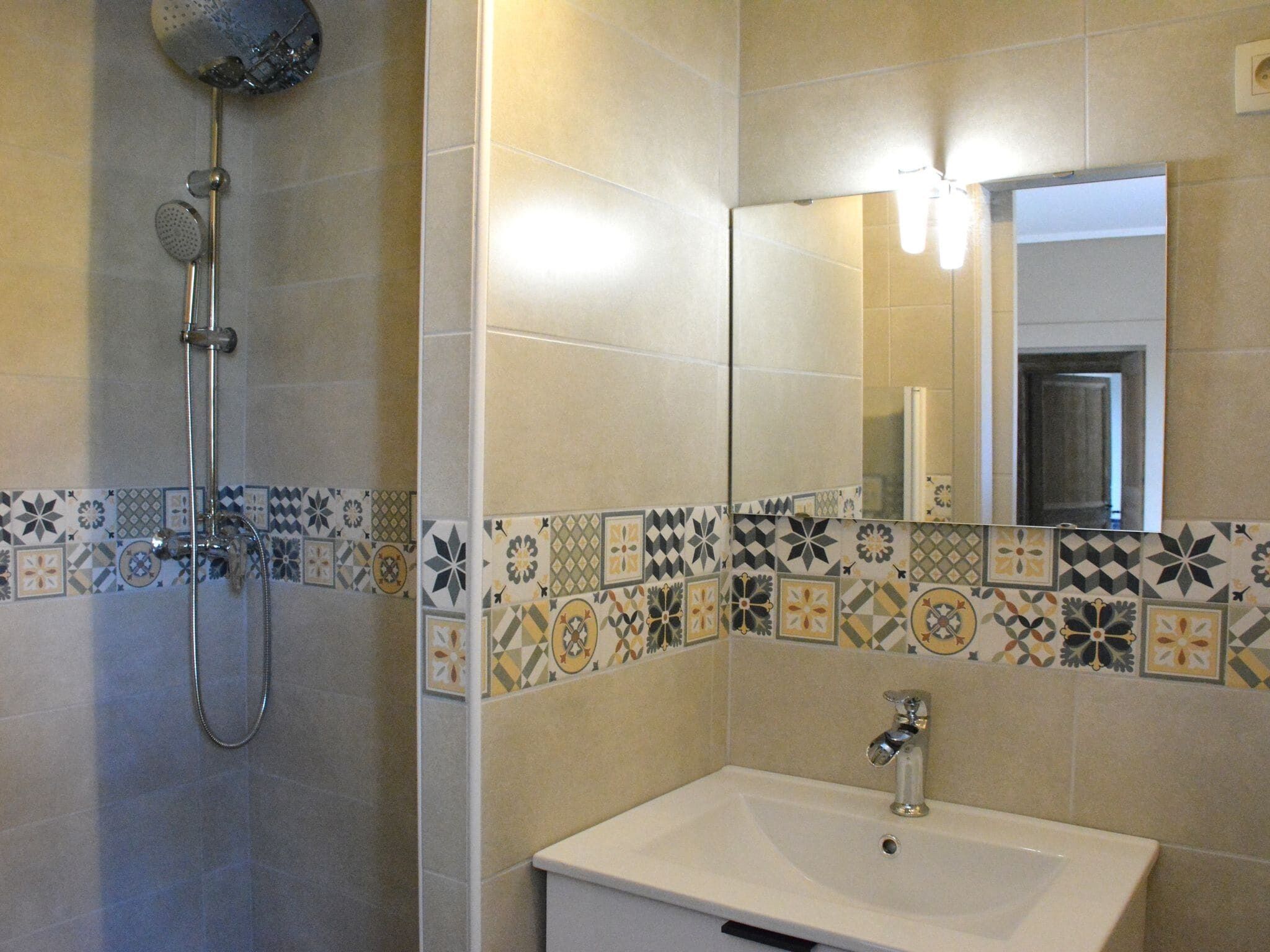 Ein Badezimmer mit Dusche, Waschbecken und Spiegel.