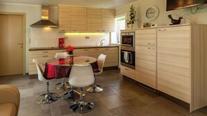 Une cuisine moderne avec un coin repas, comprenant une table ronde, des chaises, des placards et un four encastré.
