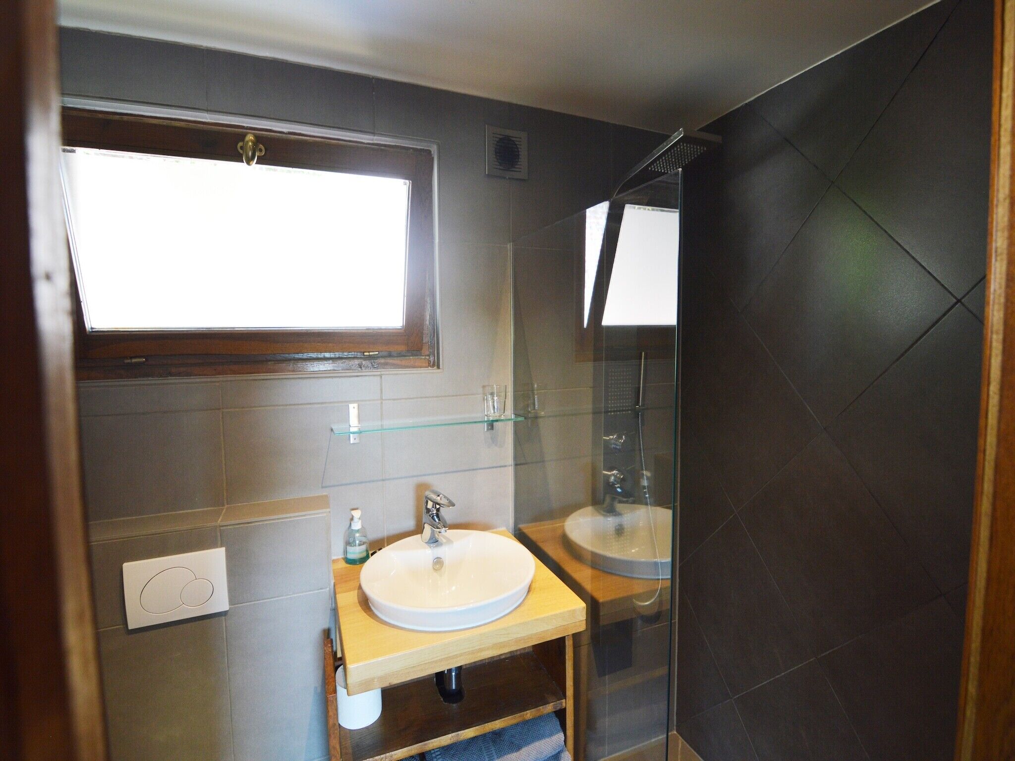Une salle de bain moderne avec un grand miroir, deux lavabos, une étagère en verre et une douche.