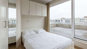 A bedroom with a bed, a wardrobe, and a large window.