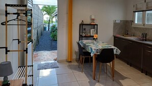 Une cuisine compacte avec un coin repas, un porte-vêtements suspendu et une vue sur l’extérieur.
