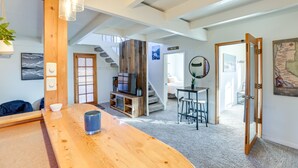 Amplia sala de estar con una mesa de centro de madera, televisor y una escalera que lleva a otro nivel.