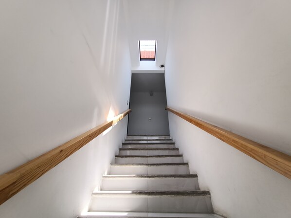 A staircase with wooden handrails, leading to a landing with a small window.