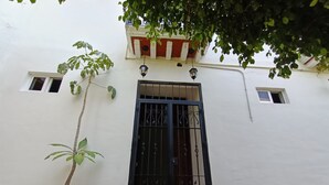 A white building with a black gate, a small window, and a potted plant. - CASA COCO OAXACA (Oaxaca)