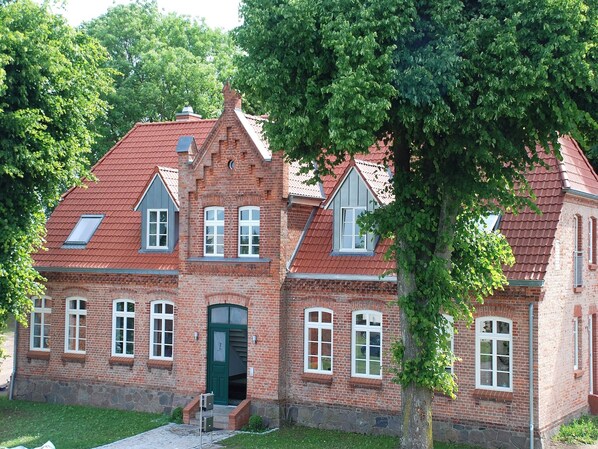 A traditional brick building with a steeply pitched roof, multiple windows, and a central entrance. - Landurlaub in Lübberstorf (Lübberstorf)