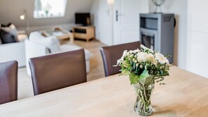 Un comedor con una mesa de madera, sillas y un jarrón de flores.