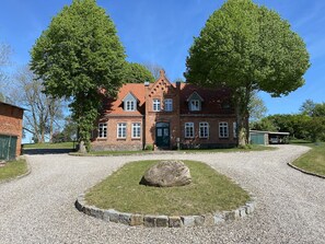 A traditional brick house with a gravel driveway and a large rock in the center. - Landurlaub in Lübberstorf (Lübberstorf)