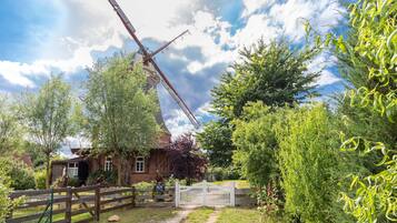 Un moulin à vent traditionnel, avec une clôture en bois et un chemin menant à un portail blanc.