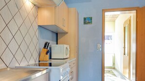 Une cuisine compacte équipée d’un four à micro-ondes, d’une cuisinière et d’un bloc à couteaux posé sur le plan de travail.