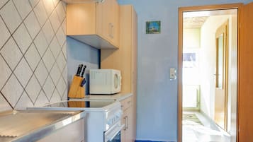 A compact kitchen with a microwave, stove, and knife block on the countertop.