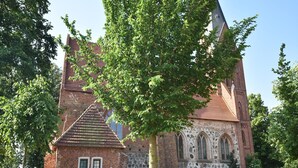 A historic church with a prominent tower, stone walls, and a small adjacent building. - Wohnung mit Garten in Damgarten (Ribnitz-Damgarten)