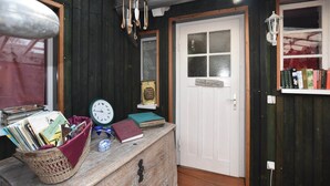 A rustic room with a wooden bench, a hanging light fixture, a door with a frosted glass window, and a shelf with books. - Wohnung mit Garten in Damgarten (Ribnitz-Damgarten)