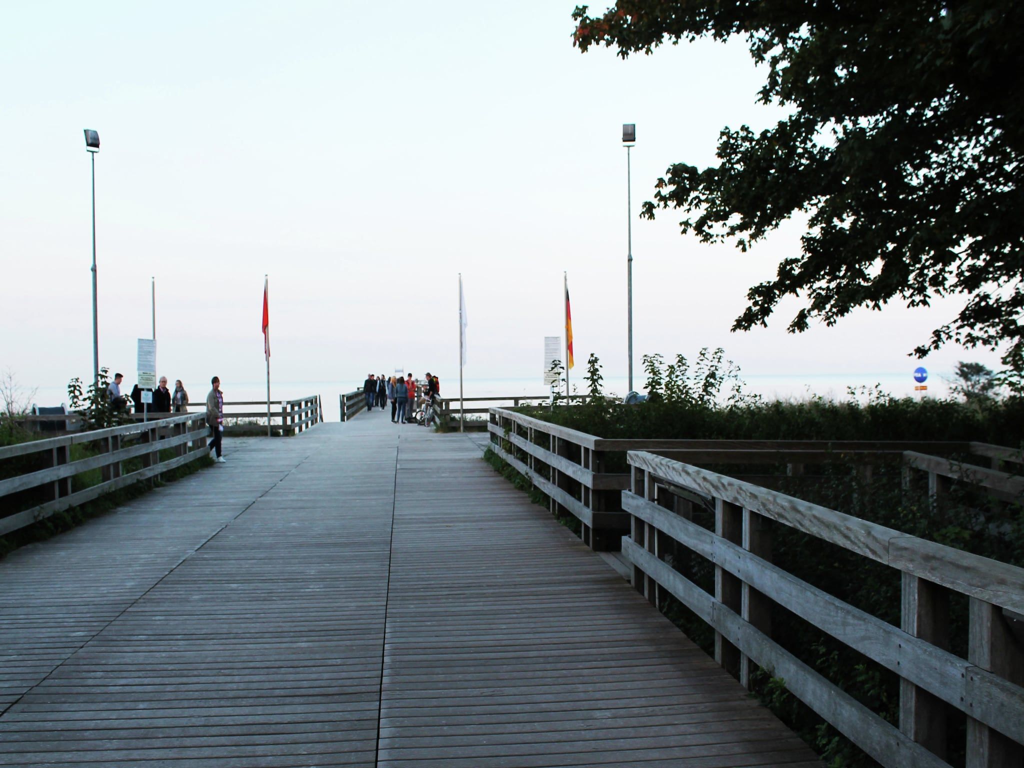 A wooden boardwalk leading to a beach with people walking.