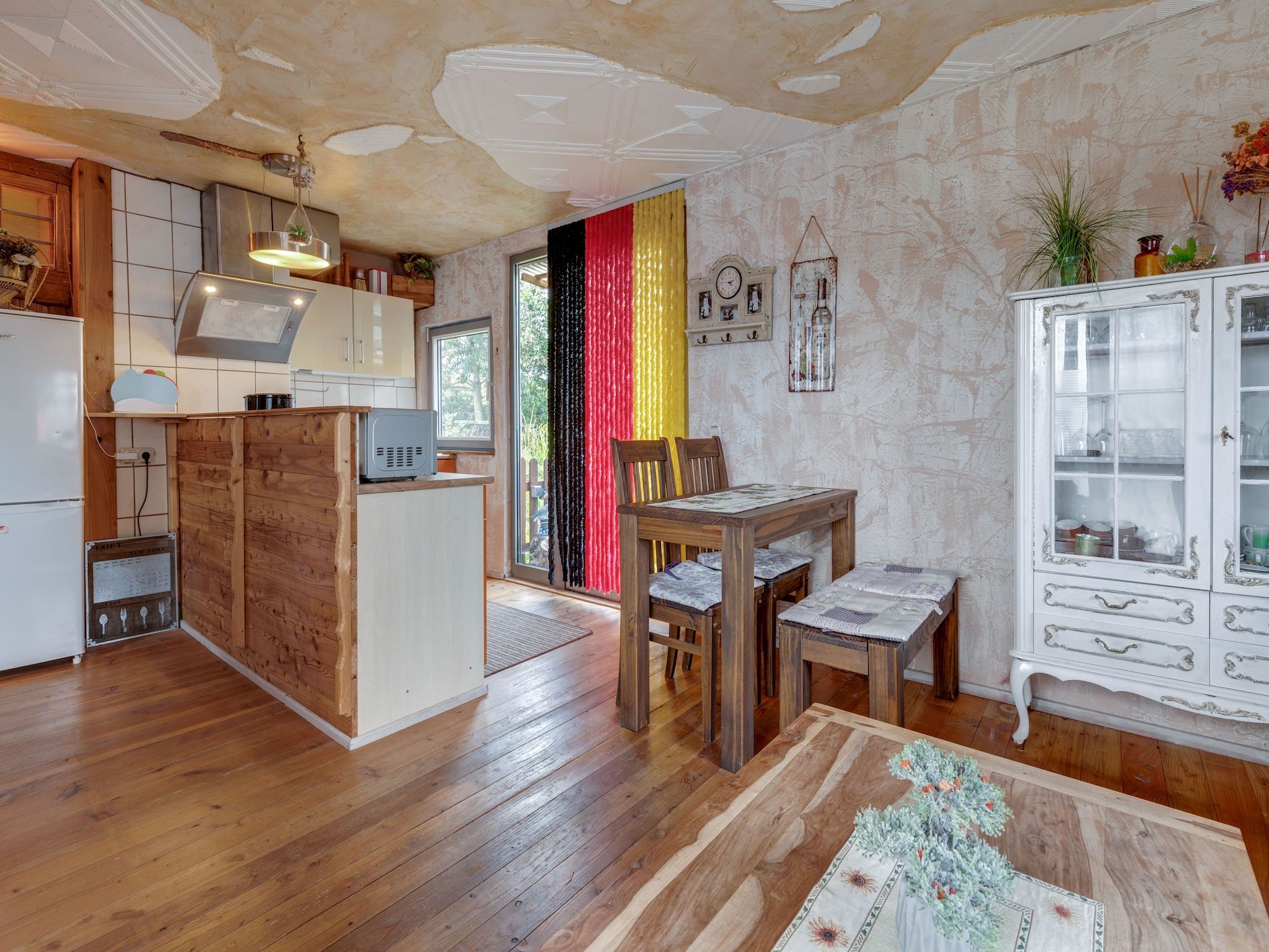 Une cuisine avec des meubles en bois, un réfrigérateur et un coin repas comprenant une table et des chaises.