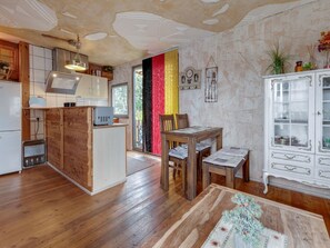 A kitchen with wooden cabinets, a refrigerator, and a dining area with a table and chairs.