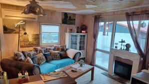 A cozy living room with a blue sofa, wooden coffee table, and a fireplace. - Gemütlicher Bungalow mit Garten in Nakenstorf (Nakensdorf)