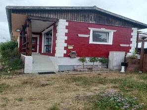 Una casa roja y blanca con puerta principal, un pequeño porche y una ventana.