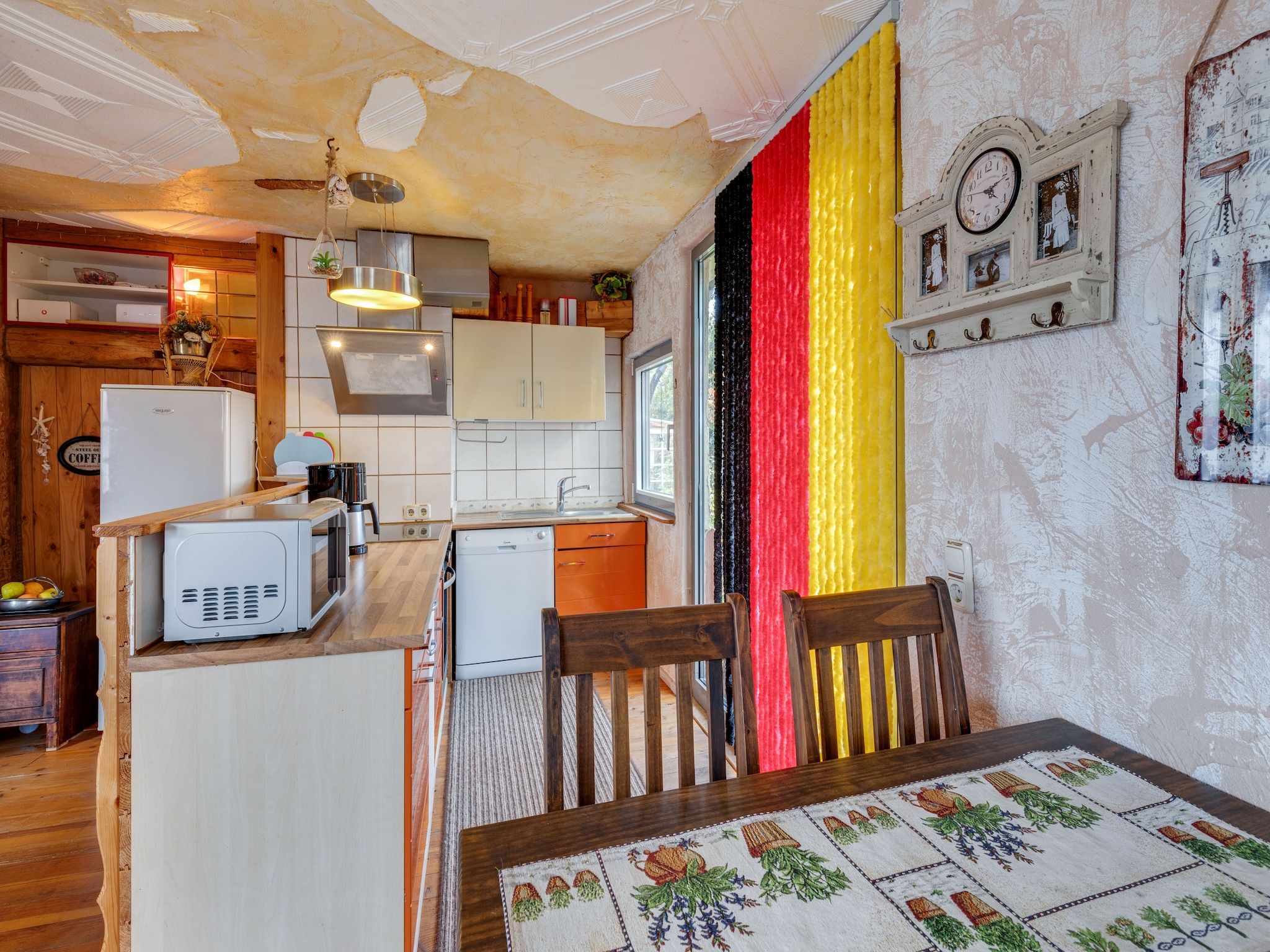 Eine kompakte Küche mit modernen Geräten, ein Essbereich mit einem Tisch und ein großes Fenster.