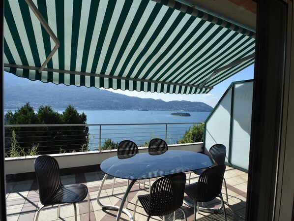 Une terrasse avec une table et des chaises, offrant une vue sur un lac et des montagnes.