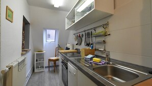 Een kleine keuken met een ingebouwde oven, een spoelbak en een raam voor natuurlijk licht.