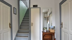 A hallway with a staircase, a door with a sign, a wooden console table with magazines, and a fire extinguisher. - Wohnung in Klütz nahe Schloss Bothmer (Klütz)