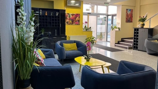 A modern lobby with a blue sofa, yellow coffee table, and a staircase leading to an upper floor. - Pensiunea Nys (Iasi)