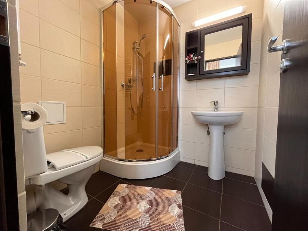 A bathroom with a glass-enclosed shower, a toilet, a sink, and a mirror.