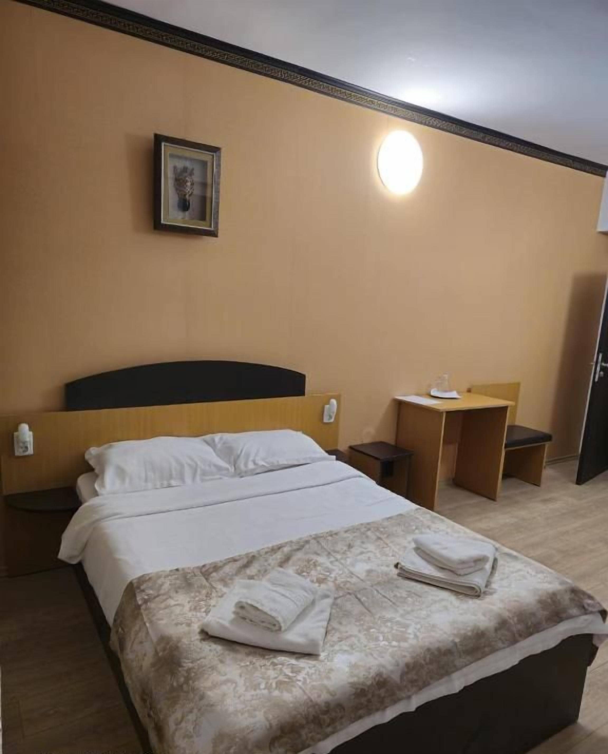 A hotel room with a Galaxy S23 Ultra bed, a bedside table, a chair, a desk, and a mirror.